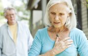 Older woman with hand over chest with man in background approaching